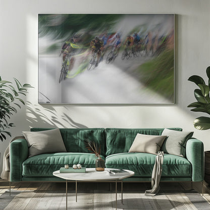 A dynamic, motion-blurred photograph of a group of cyclists in a race, captured with a slow shutter speed to create streaks of color and a sense of high speed. The lead cyclist in a yellow and black jersey is the most defined figure, leaning into a turn on a grey road flanked by blurry green foliage. The entire image is enclosed in a silver frame. Decor