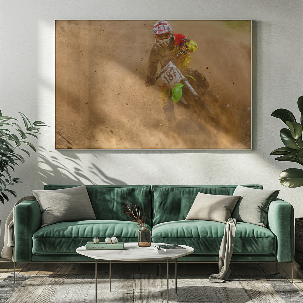 An action shot of a motocross rider in full red and yellow gear, speeding through a dirt track and kicking up a large cloud of brown dust and debris. Print