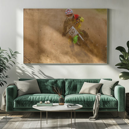 An action shot of a motocross rider in full red and yellow gear, speeding through a dirt track and kicking up a large cloud of brown dust and debris. Print