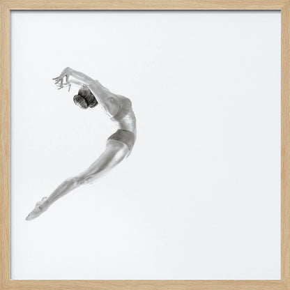 A minimalist black and white photograph of a graceful dancer frozen in mid-air, her body arched backward in an elegant C-shape against a stark white background. The artwork is presented in a light wood frame. Decor