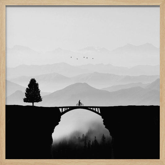 A minimalist black and white artwork featuring the silhouette of a cyclist crossing a high arched bridge between two cliffs. A lone tree stands on one cliff, while layers of misty mountains fill the background, creating a sense of depth and solitude. Poster