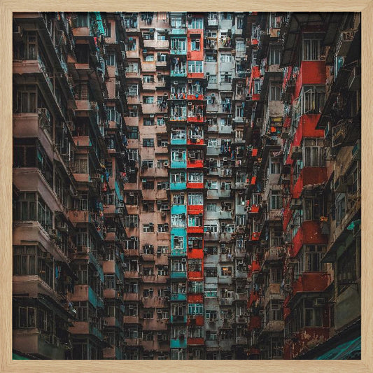 A framed, low-angle photograph looking up at densely packed, weathered apartment buildings that create a canyon-like view, with some facades painted in vibrant red and teal. Wall Art