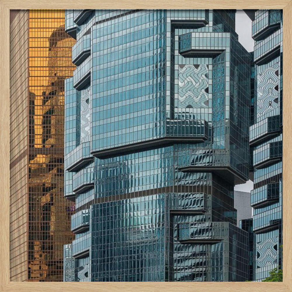 A framed close-up photograph of modern architecture, featuring a golden grid-patterned skyscraper next to a complex blue glass building with jutting levels and distorted reflections. Wall Art
