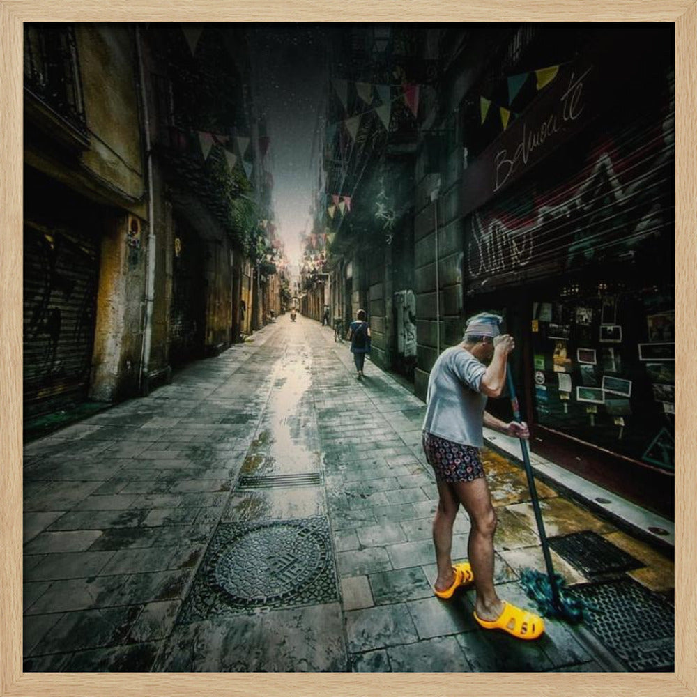 A wide-angle, atmospheric photograph of a man in bright yellow clogs mopping a wet, narrow cobblestone alley. The dark, gritty city street is lined with old buildings and closed storefronts, with another person walking in the distant light at the end of the alley. Wall Art