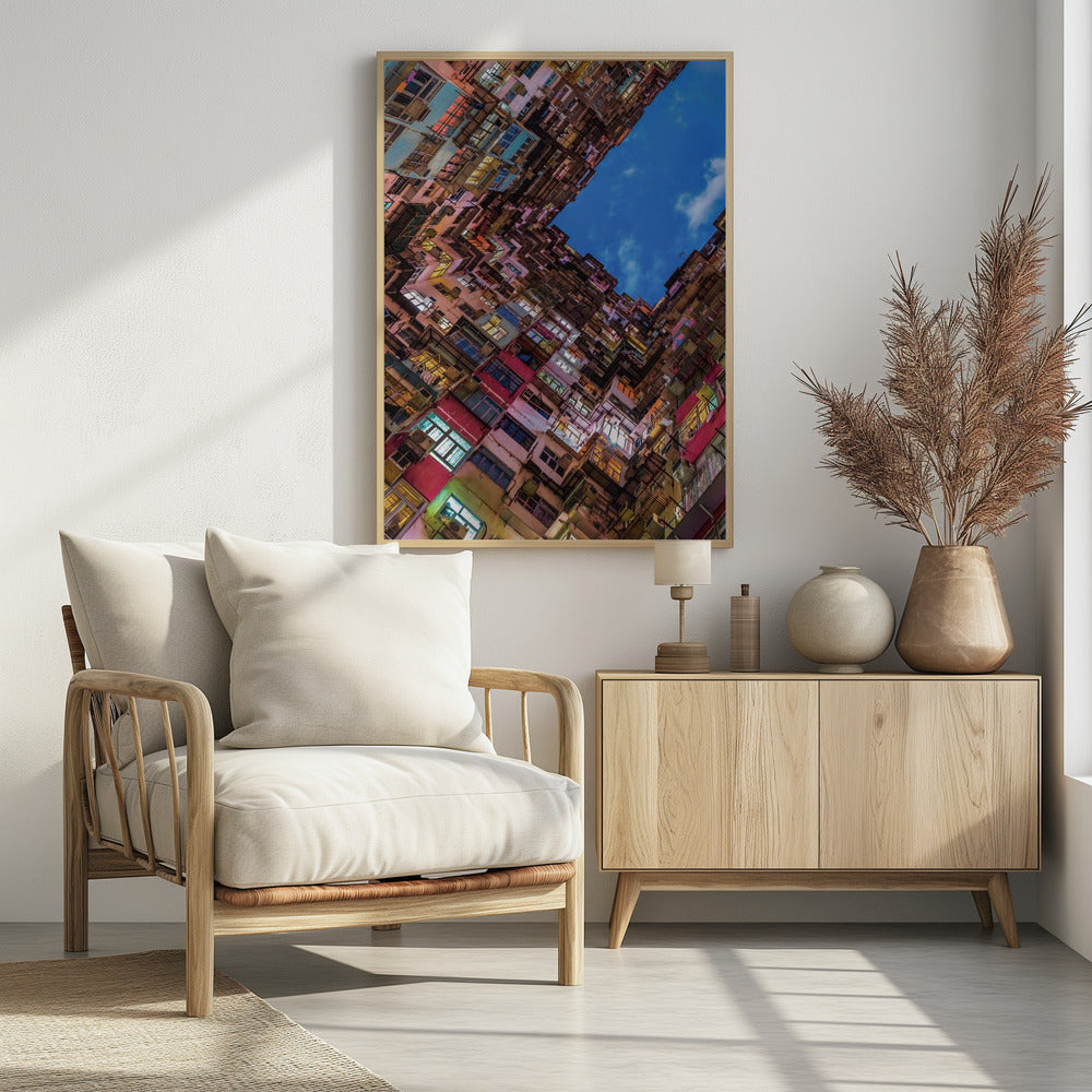 A dramatic worm's-eye view looking up at colorful, densely packed high-rise apartment buildings that create a geometric frame around a patch of deep blue sky. Wall Art