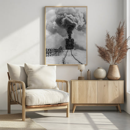 A dramatic black and white photograph of a vintage steam train on tracks in a snowy landscape, viewed from a low angle. A massive, powerful plume of dark smoke billows from the smokestack, filling the sky. Decor