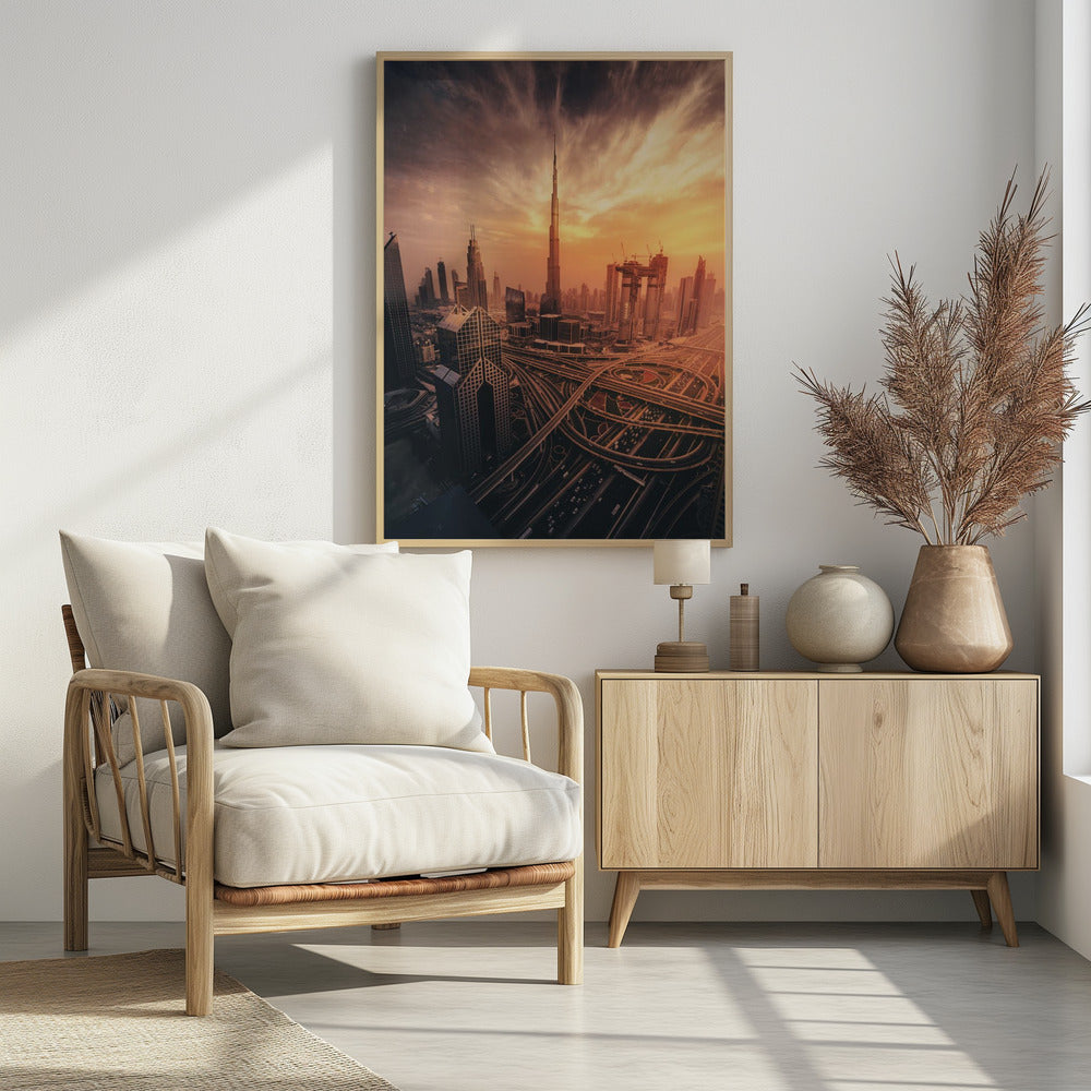 A dramatic high-angle photograph of the Dubai skyline at sunset. The Burj Khalifa stands tall in the center, bathed in the warm light of the setting sun, while a complex network of highways and interchanges weaves between modern skyscrapers in the foreground under a cloudy, orange-tinted sky. Poster