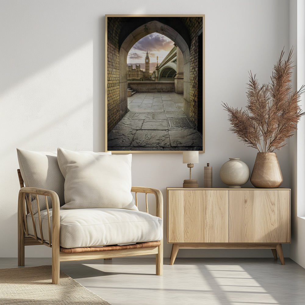 A scenic view of London's Big Ben clock tower and the Houses of Parliament as seen through a weathered stone archway. The foreground features a stone-paved walkway, and the background shows the iconic landmarks against a cloudy sunset sky with hues of purple and orange. Poster
