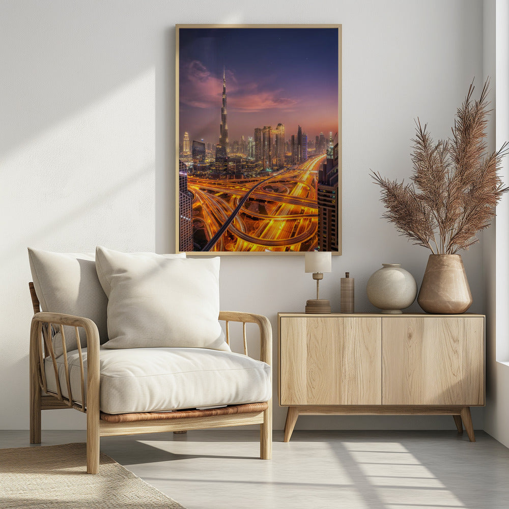 A stunning aerial photograph of the Dubai skyline at dusk, featuring the illuminated Burj Khalifa against a purple and pink sunset sky. In the foreground, complex highway interchanges are aglow with the golden-orange light trails of moving traffic, creating a sense of vibrant energy. Poster