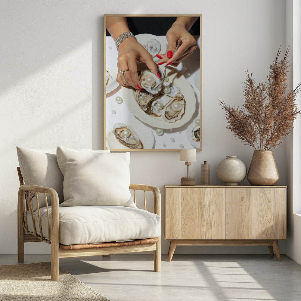 A close-up overhead shot of a woman's hands with vibrant red nails and elegant jewelry, using a fork to lift a large pearl from an oyster shell on a white plate. The plate and the surrounding white surface are adorned with numerous oysters filled with pearls of varying sizes, creating a luxurious and surreal scene. Print