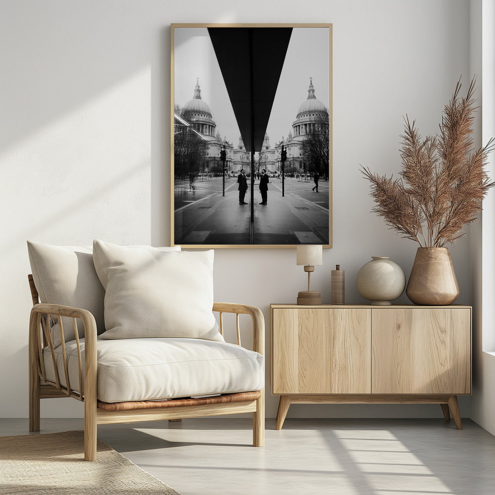 A surreal black and white photograph capturing a symmetrical reflection of a city scene, with St. Paul's Cathedral prominently featured on both sides. A dark, V-shaped reflection from a building divides the image vertically. In the foreground, the reflection of two men in dark suits standing on the sidewalk adds a human element to the grand architectural view. Decor