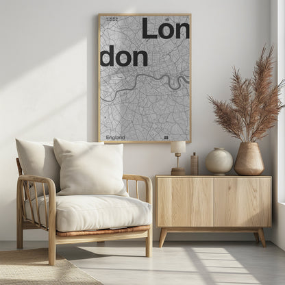 A framed, minimalist black and white street map of London. The word 'London' is split into two lines, 'Lon' and 'don', in large, bold black font overlaid on the light grey map. The River Thames snakes through the center in a darker grey, matching the intricate street grid. Coordinates are in the top left corner, and 'England' is in the bottom left. Decor