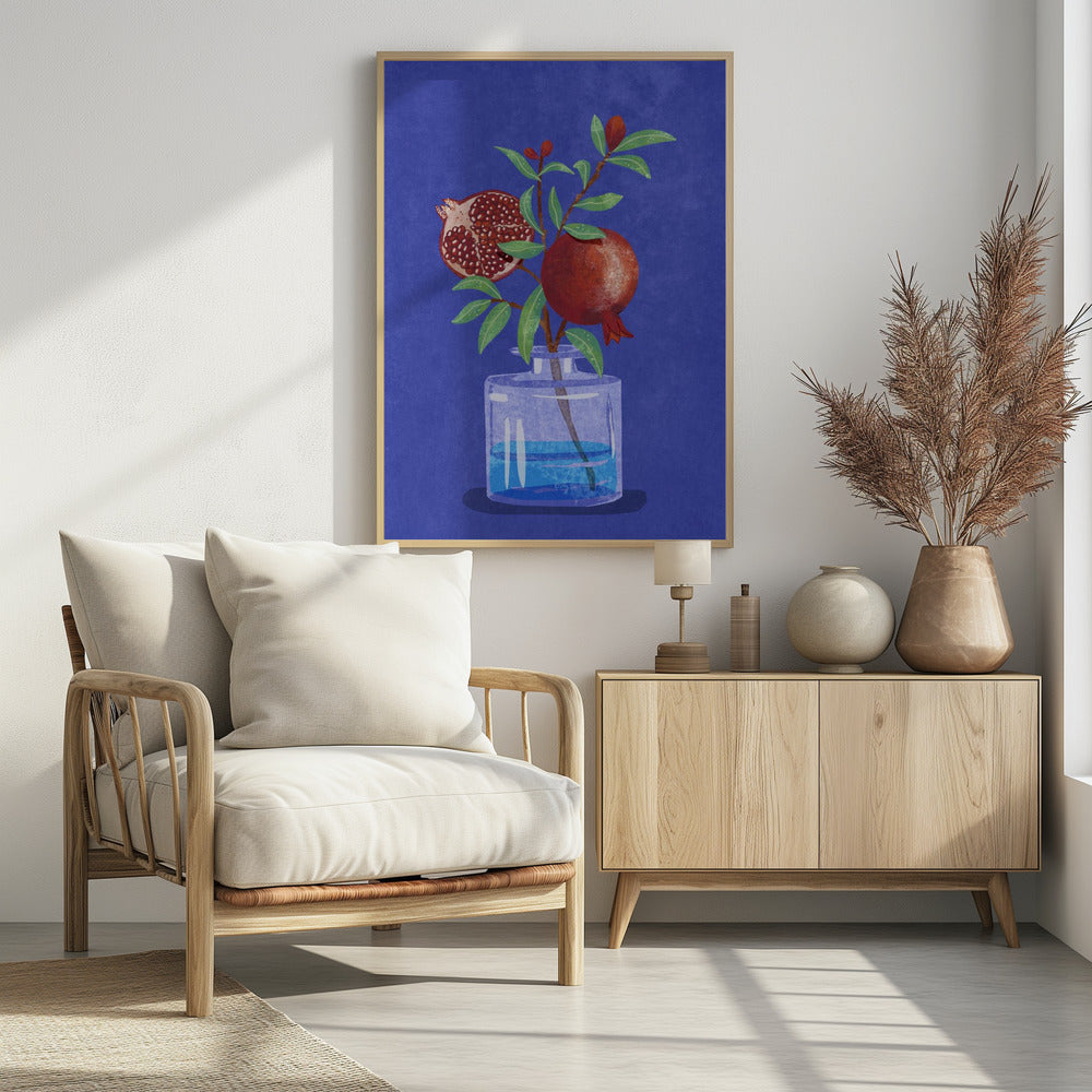 A vibrant illustration of a pomegranate branch in a clear glass vase against a deep blue, textured background. The branch features bright green leaves, a whole red pomegranate, and another cut in half to show its seeds. Decor
