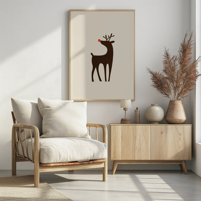 A minimalist art print of a stylized brown reindeer with a bright red nose, standing in profile against a cream-colored background, all enclosed in a simple black frame. Print