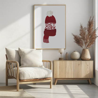 A minimalist illustration of a red knit beanie with a white pom-pom and a matching red scarf. The words 'GET COZY' are written in a playful font, forming the middle section of the hat and scarf against a plain white background, enclosed in a black frame. Poster