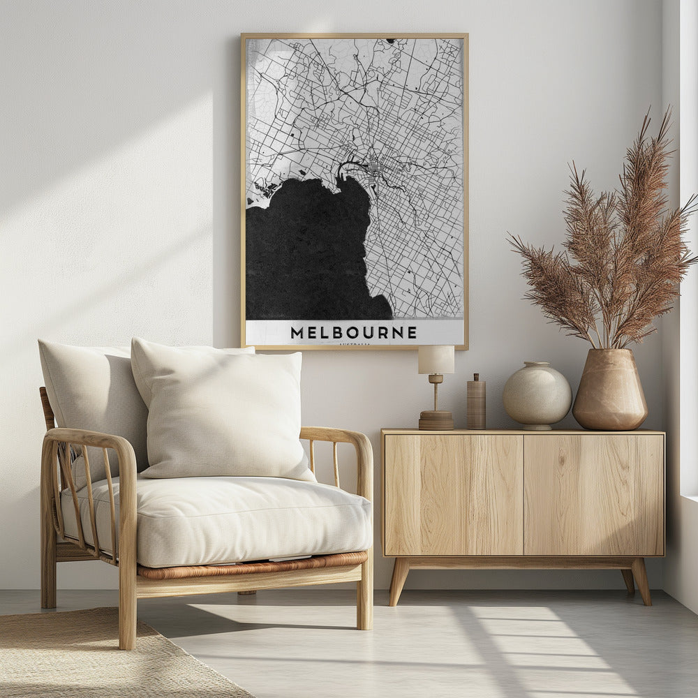 A minimalist black and white map of Melbourne, Australia, presented in a black frame. The city's road network is depicted with fine black lines on a textured white background, while the adjacent bay is shown in solid, textured black. The name 'MELBOURNE' is written in a bold, black font at the bottom. Poster
