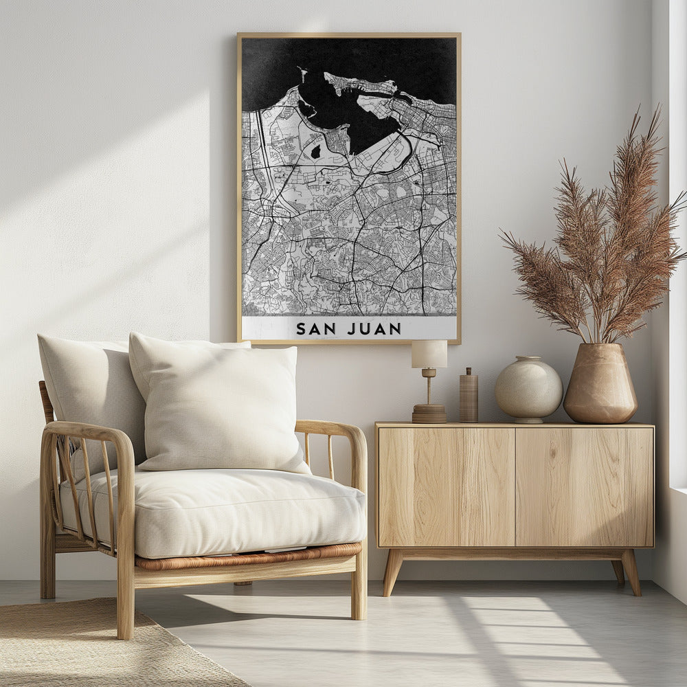 A minimalist black and white map of San Juan, Puerto Rico, shown as a framed poster. The land is depicted in white with intricate black lines for roads and streets, while the surrounding water is a solid, textured black. A white banner at the bottom features the text 'SAN JUAN' in a bold, black, sans-serif font. Artwork