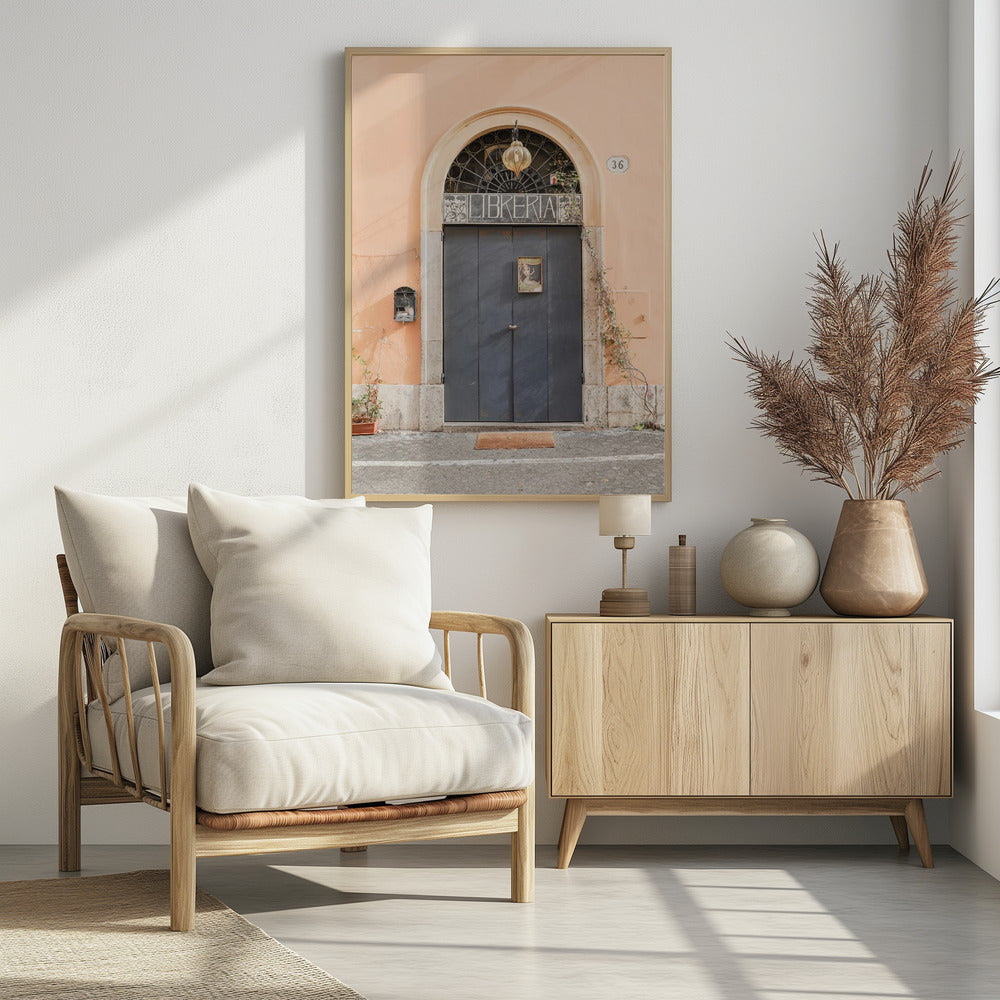 A charming European bookstore entrance featuring a large, dark grey arched door set against a peach-colored wall. Above the door, a sign reads 'LIBRERIA' below a decorative fanlight window and a hanging lantern. Decor