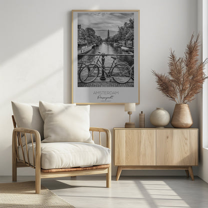 A black and white poster of the Prinsengracht canal in Amsterdam. A bicycle is parked on a bridge in the foreground, overlooking the canal lined with houseboats, trees, and traditional Dutch buildings. The Westerkerk church tower is visible in the distance. The poster has a white border with the words 'AMSTERDAM', 'Prinsengracht', and 'NEDERLAND' at the bottom. Poster