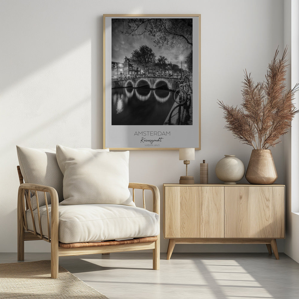 A black and white poster of Amsterdam's Keizersgracht canal at night. An arched bridge with glowing lights is the centerpiece, its reflection shimmering on the dark water. Bicycles are parked along the bridge and in the foreground on a cobblestone path. Classic canal houses and trees line the background under a dramatic, cloudy sky. The image is framed with text below reading 'AMSTERDAM Keizersgracht NEDERLAND'. Artwork