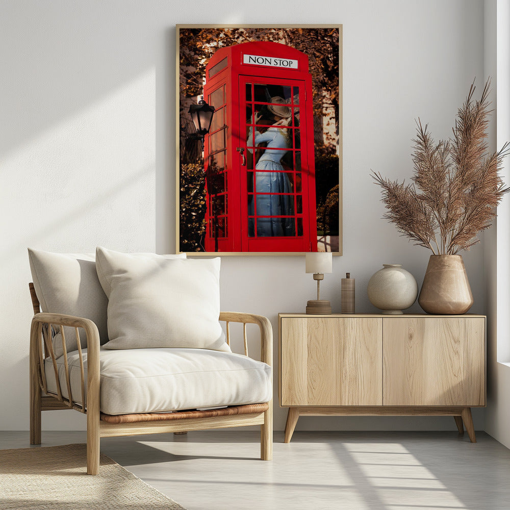A couple in vintage clothing share a passionate kiss inside a classic bright red telephone booth. The woman is wearing a light blue dress, and the man wears a hat. The sign above the booth door reads 'NON STOP'. The setting appears to be outdoors in autumn. Wall Art