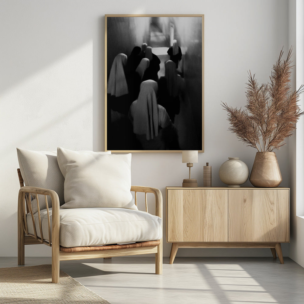 A mysterious black and white photograph captures a group of robed figures, possibly nuns, from above as they walk down a dark, narrow corridor. The image is blurred, creating a ghostly, ethereal atmosphere as the figures' white head coverings stand out against the deep shadows. Artwork