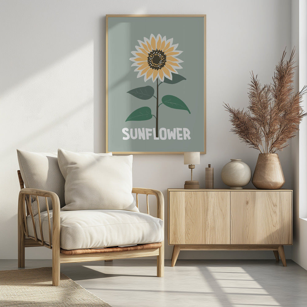 A stylized illustration of a single sunflower against a muted sage green background. The flower has yellow and white petals, a dark brown center, and a thin brown stem with green leaves. At the bottom, the word 'SUNFLOWER' is written in a bold, white, sans-serif font. The artwork is presented within a simple black frame. Decor
