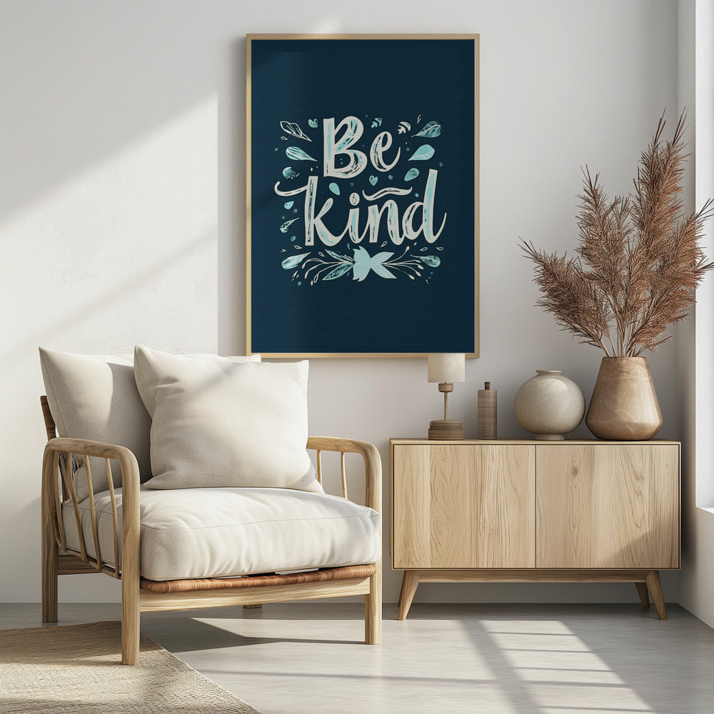 An inspirational art print with a dark blue background featuring the phrase 'Be Kind' in a stylized, hand-lettered white and light blue font. The text is decorated with small leaves, hearts, and flourishes in shades of teal and white. Artwork