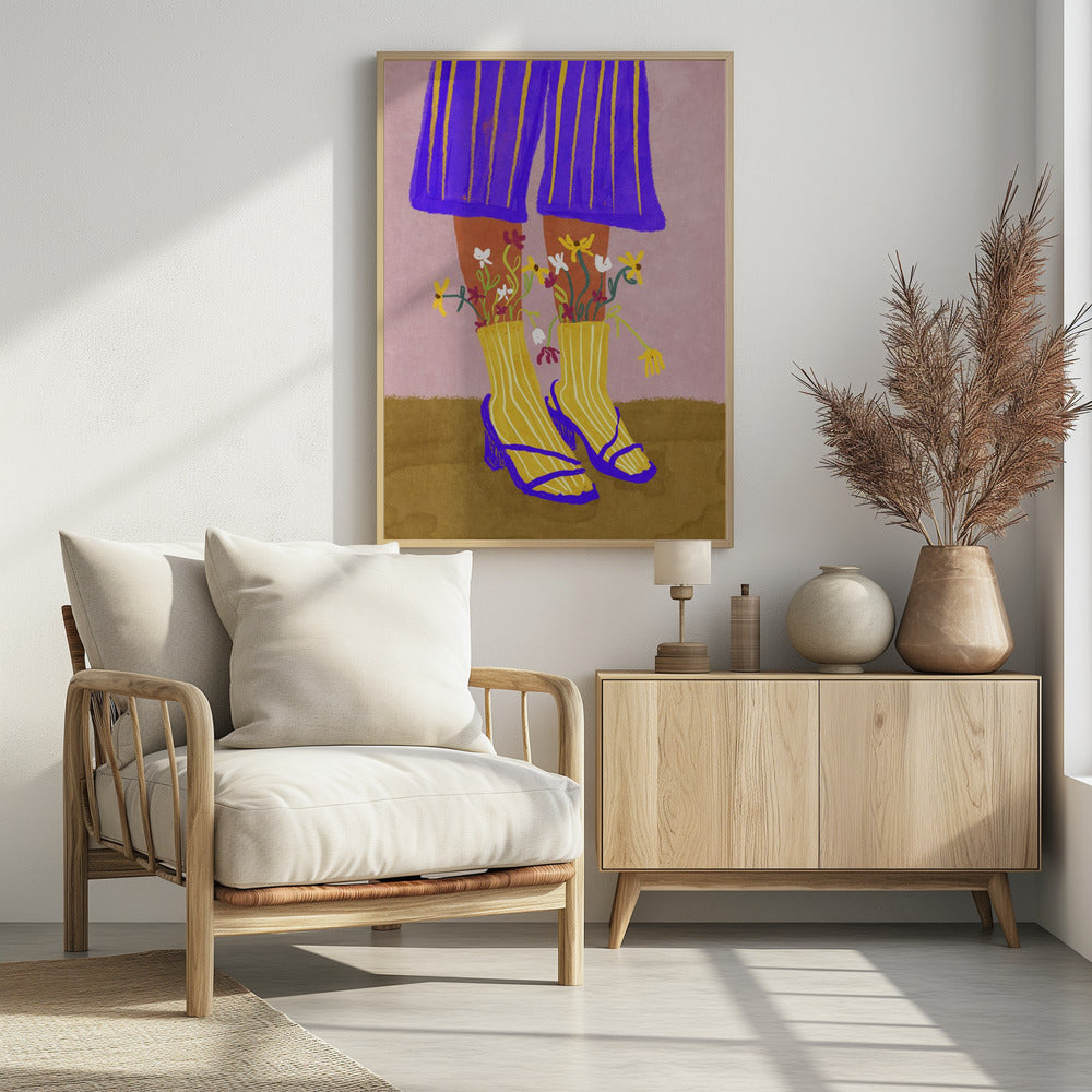 A stylized, colorful illustration focusing on the lower legs and feet of a person wearing vibrant clothing. They have on wide-legged, royal blue trousers with vertical yellow stripes, and yellow socks with white stripes. Small, colorful wildflowers sprout from the tops of their socks. They are wearing bright blue strappy heeled sandals. The background is a soft pink color with a brown floor. Wall Art
