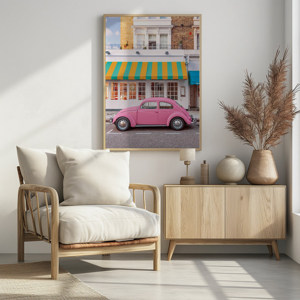 A vibrant, eye-level photograph of a vintage pink Volkswagen Beetle parked on a city street in front of a charming white storefront with a bold yellow and teal striped awning. Wall Art