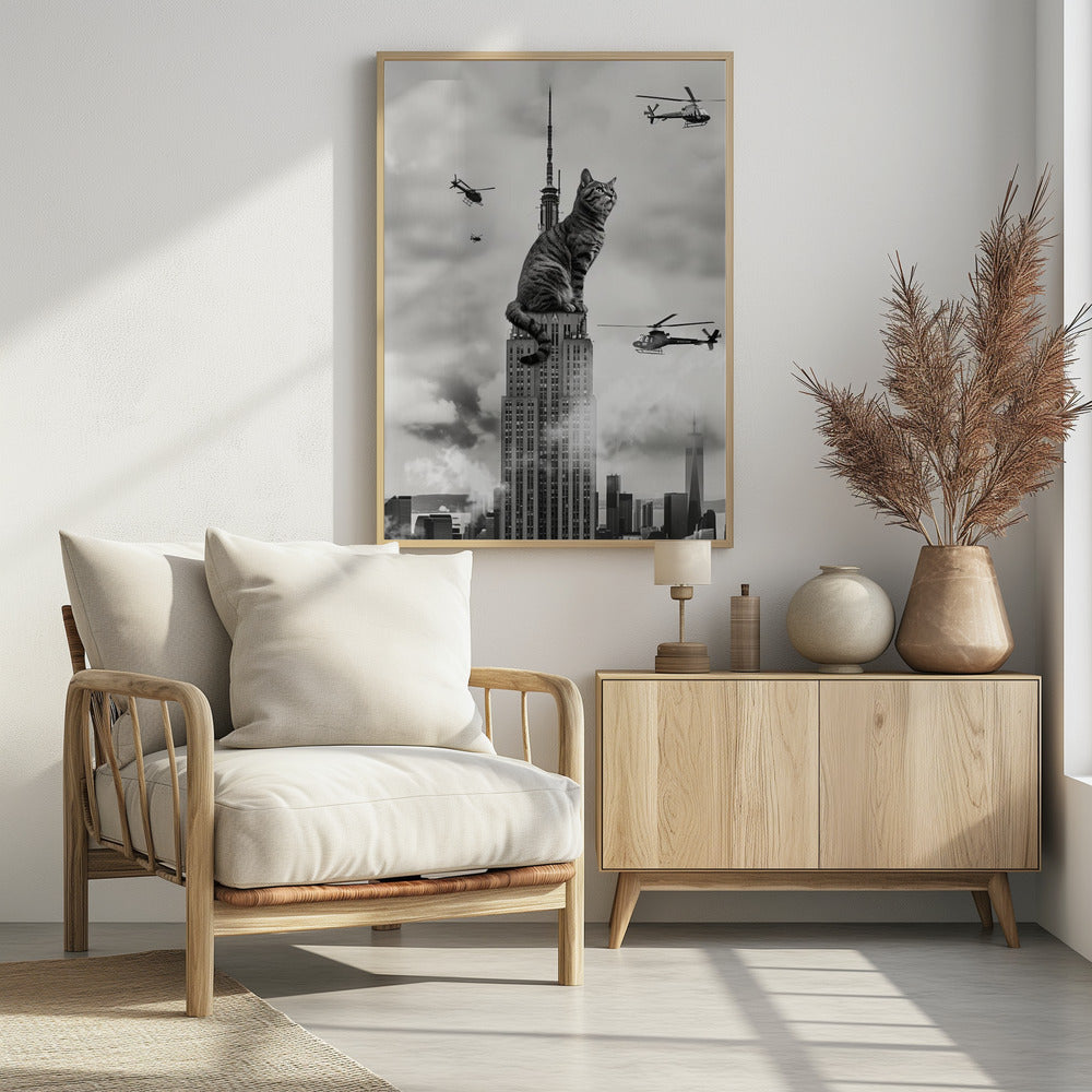 A surreal black and white image depicting a giant tabby cat sitting on top of the Empire State Building, similar to King Kong. Helicopters fly around the colossal cat against a cloudy New York City skyline. Decor