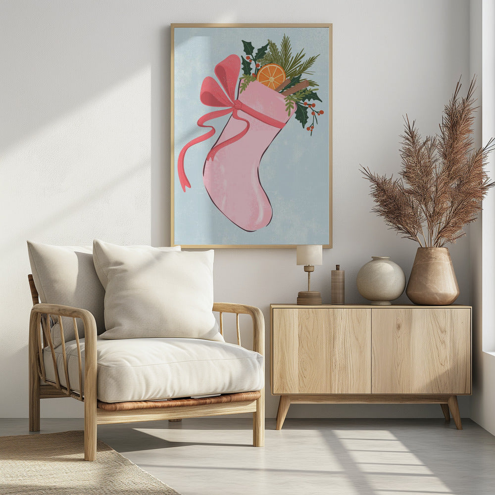 A festive illustration of a pink Christmas stocking against a light blue textured background. The stocking is tied with a large pink ribbon and is filled with holiday greenery, including holly with red berries, pine needles, a slice of dried orange, and cinnamon sticks. Decor
