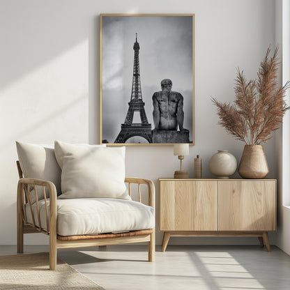A black and white photograph capturing a contemplative scene in Paris, with the back of a seated, muscular male stone statue in the foreground looking towards the iconic Eiffel Tower which stands tall against a cloudy sky. Print