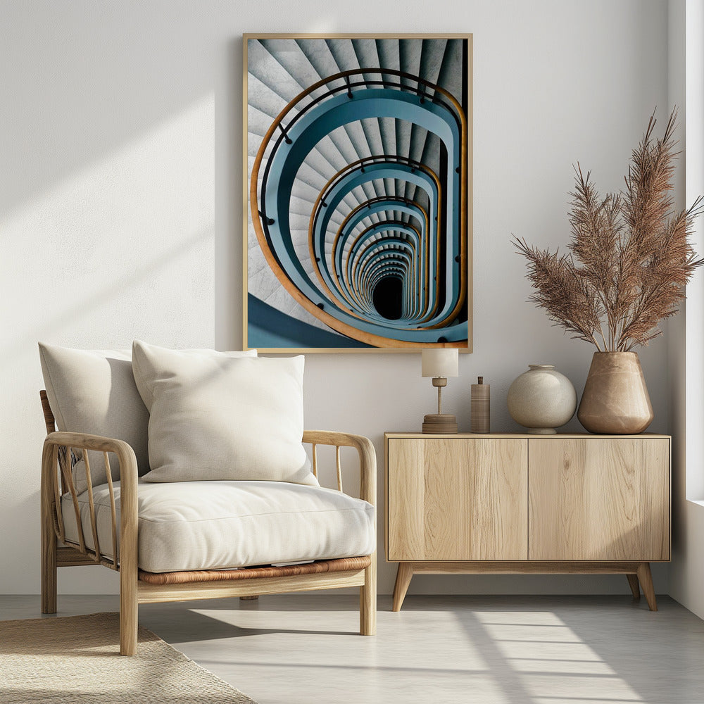 A high-angle, top-down photograph of a multi-story rectangular spiral staircase, creating a hypnotic, receding pattern. The steps are light gray marble, contrasted by shadows, and the balustrade is a striking light blue with a warm wooden handrail, leading down to a dark abyss at the center. Wall Art
