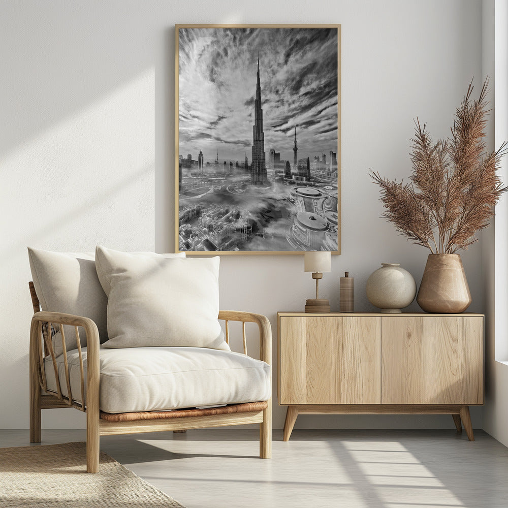 A dramatic black and white high-angle photograph of the Burj Khalifa dominating the Dubai cityscape, with swirling clouds above and a light mist surrounding the buildings below, all enclosed in a black frame. Poster