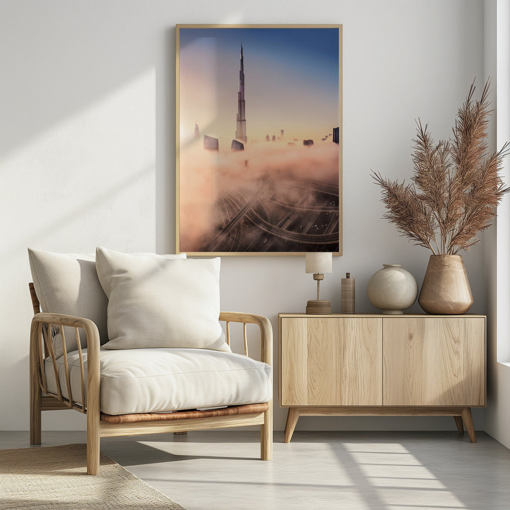 An aerial photograph of the Burj Khalifa in Dubai, towering over a thick blanket of pink and orange-hued fog at sunrise. Below the fog, a complex highway interchange is visible, with the clear blue sky above. Wall Art