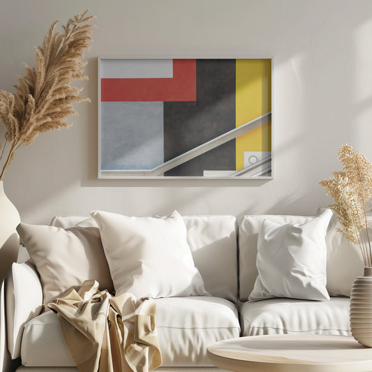 A framed abstract art piece featuring a composition of large, solid-colored geometric shapes in red, yellow, black, white, and light gray. A silver handrail cuts diagonally across the lower portion of the image, adding a sharp line and a sense of architectural space. Artwork