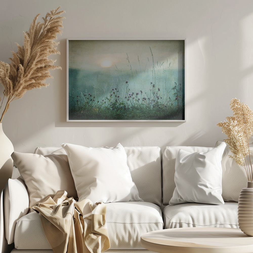 A framed photograph of a misty meadow at sunrise. The soft, pale sun hangs in a hazy, textured sky. In the foreground, tall green grasses and small purple wildflowers are in soft focus, creating a serene and dreamy atmosphere. Decor