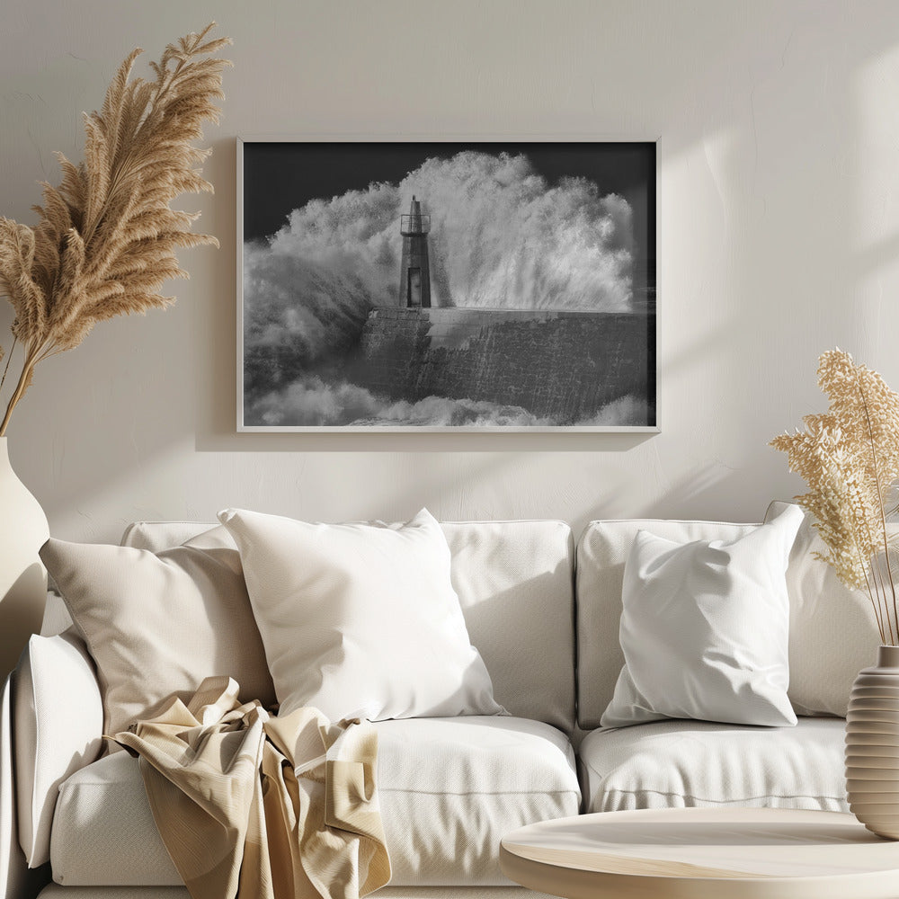 A dramatic black and white photograph of a massive wave crashing against a stone pier and a small lighthouse. The white foam of the wave towers over the structure, creating a powerful and dynamic scene against a dark sky, all enclosed in a silver frame. Poster