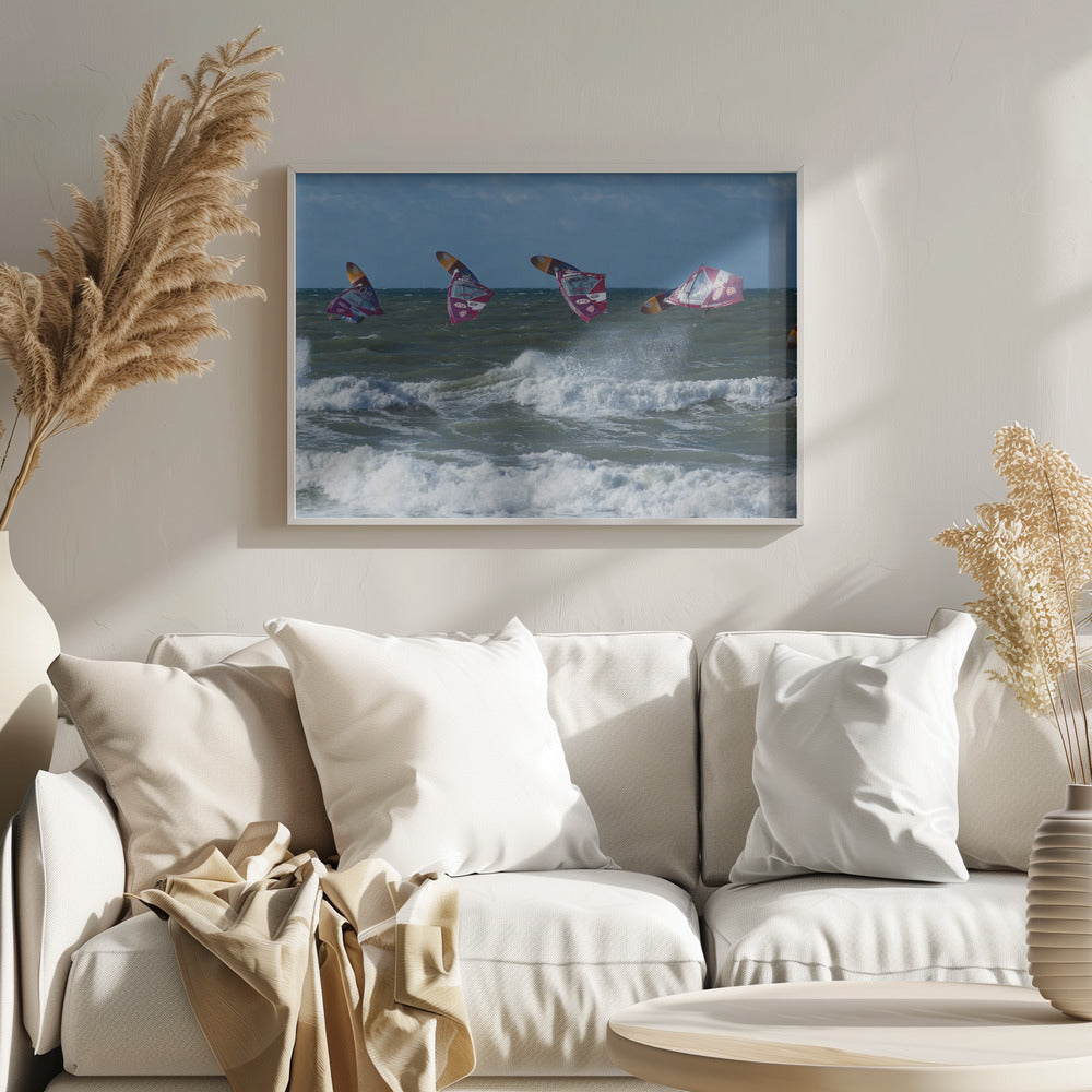 A composite, silver-framed photograph capturing the four stages of a windsurfer's impressive jump over choppy, white-capped ocean waves under a partly cloudy blue sky. Print