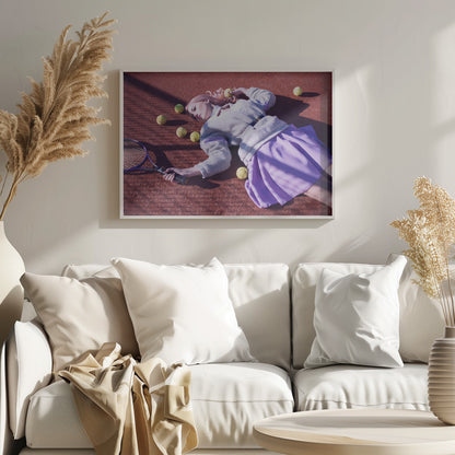 A high-angle shot of a young woman with pink hair lying on a red clay tennis court, surrounded by yellow tennis balls. She wears a grey sweater, a white collared shirt, and a purple pleated skirt, and holds a tennis racket in one hand. The scene is framed with a silver border. Wall Art