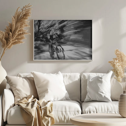 A dramatic black and white action shot of a professional cyclist racing. The cyclist is in focus, wearing a helmet and sunglasses, while the background is a streaky motion blur, creating a powerful sense of speed and movement. The image is enclosed in a silver frame. Wall Art