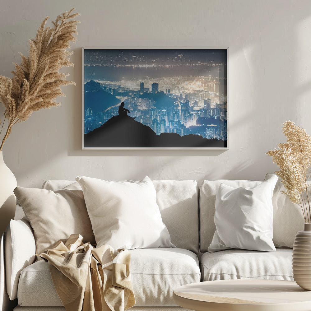 A silhouette of a person sitting on a hilltop, gazing out over a vast, illuminated city skyline at night. The city lights glow in shades of blue and gold against the dark landscape, with a body of water in the distance. Decor