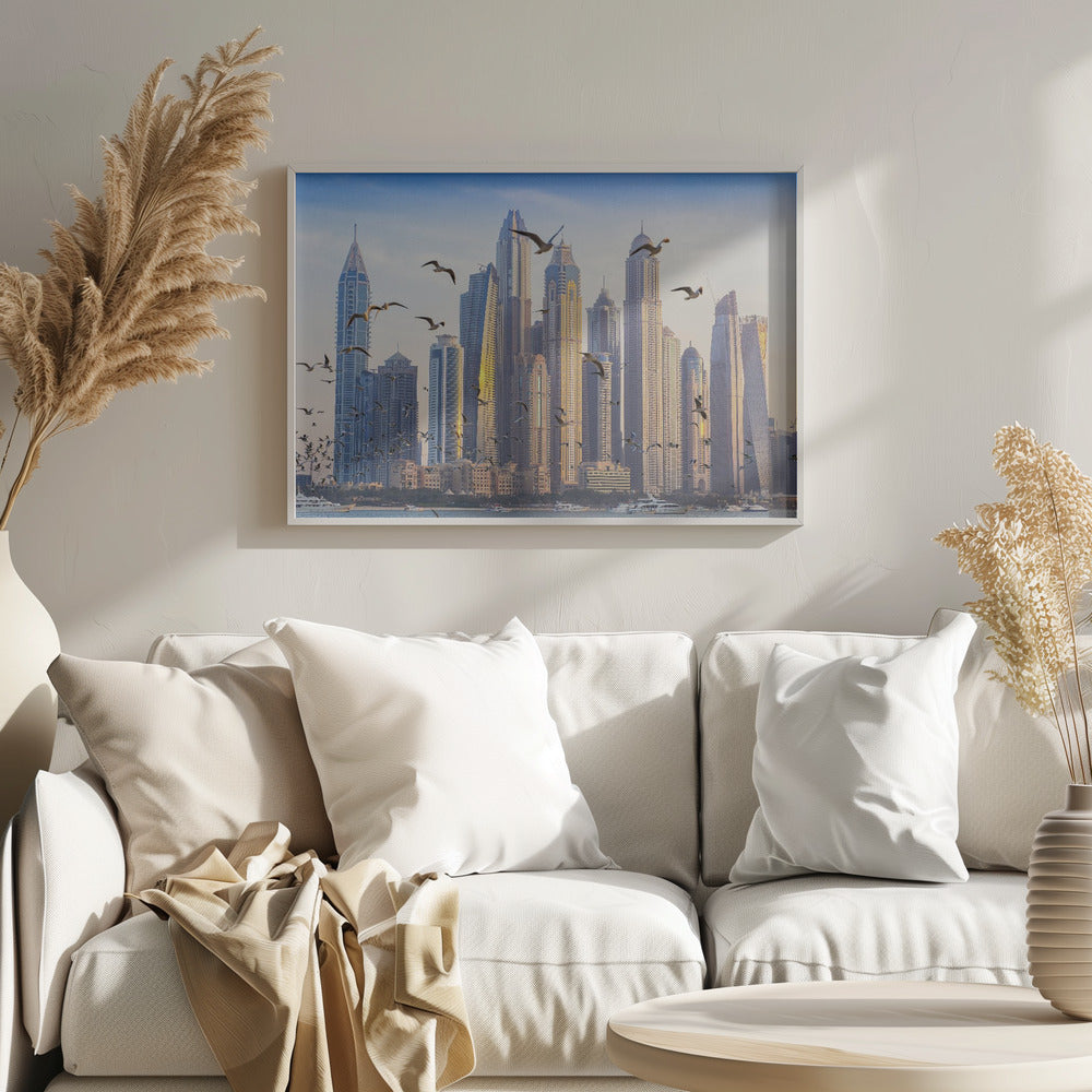 A framed artwork of the Dubai city skyline, featuring modern skyscrapers bathed in the golden light of sunset. A flock of seagulls flies in the foreground above the water, where several yachts are docked. Artwork