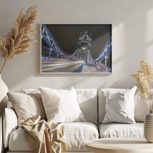 A dramatic, long-exposure night photograph from the deck of London's Tower Bridge, showing vibrant blue support structures curving towards an illuminated stone tower against a dark sky, with bright streaks of light from traffic. Wall Art