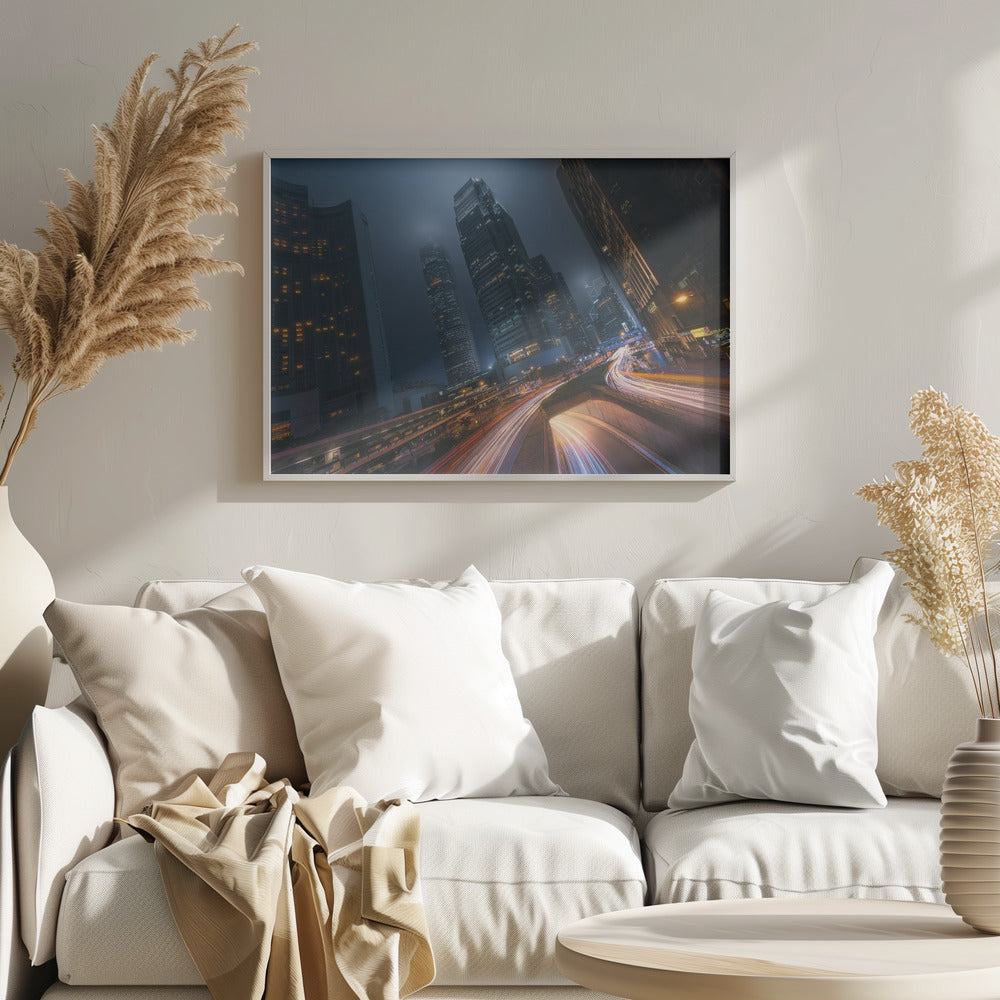 A framed, low-angle photograph capturing a bustling city at night, with towering skyscrapers shrouded in fog. Long-exposure creates vibrant streaks of light from traffic on a multi-level highway, illuminating the dark, modern urban landscape. Wall Art
