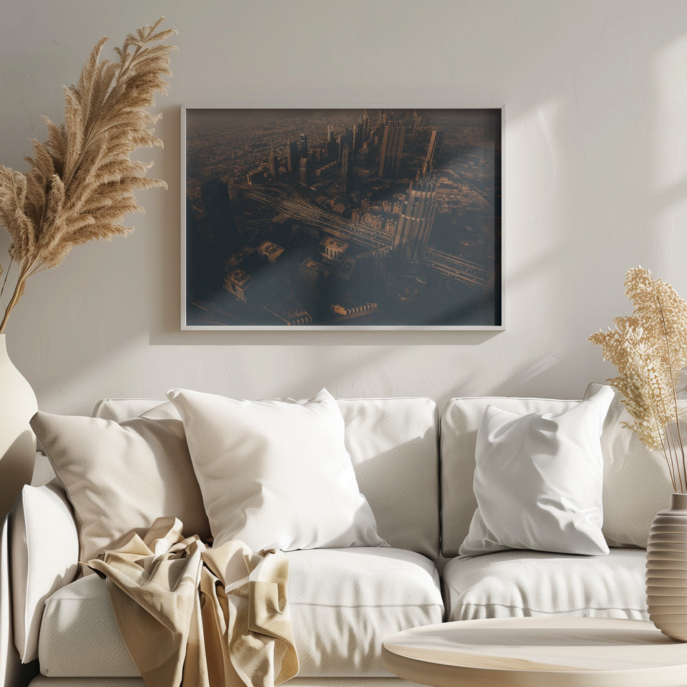 An aerial view of a sprawling modern city at dusk, with the warm glow of sunset casting long shadows over skyscrapers and illuminating a complex network of highways. The photograph has a warm, sepia-like tone and is presented within a silver-colored frame. Decor