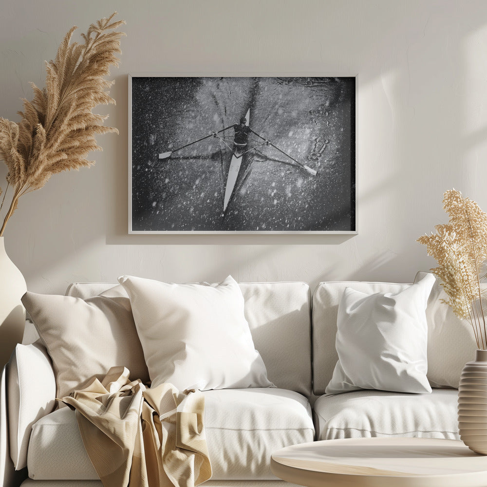 A dramatic black and white overhead photograph of a single rower in a narrow scull, captured mid-stroke as they cut through dark water during a heavy snowfall, creating a high-contrast and atmospheric scene. Decor