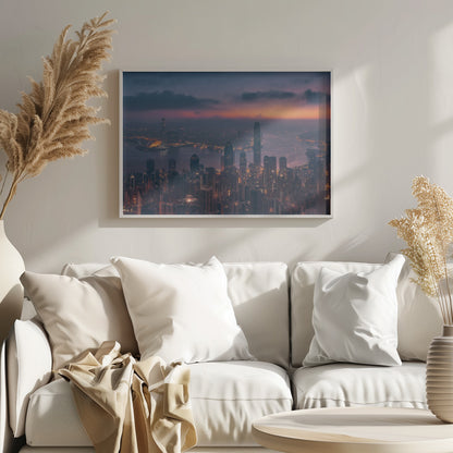 An aerial photograph of a sprawling city skyline at dusk, likely Hong Kong, with countless illuminated skyscrapers. The sky above transitions from a warm orange glow at the horizon to a deep purple, with dark clouds overhead. The city lights cast a golden reflection on the water of the harbor. The entire image is presented within a silver-colored frame. Poster