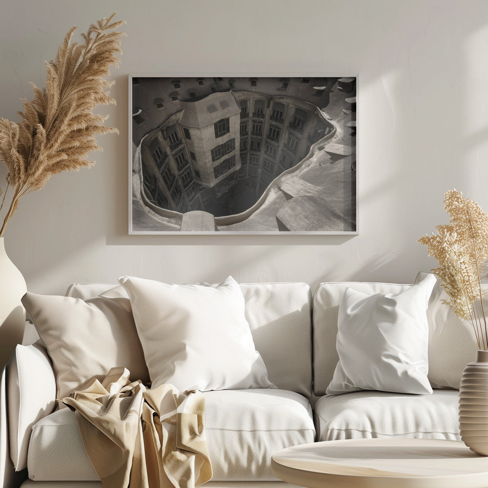 A surreal, high-angle photograph looking down into the distorted, cavernous courtyard of a building. The walls and windows appear to melt and curve inwards towards a dark void, creating a powerful optical illusion. The image has a muted, sepia-toned color palette and is presented in a silver frame. Wall Art
